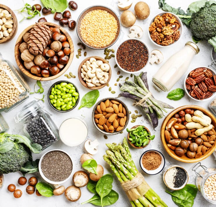 Különböző vegán, növényi alapú fehérjeforrások egy asztalon, felülről fotozóva: magvak, hüvelyesek, tofu, borsófehérje és még sok más.