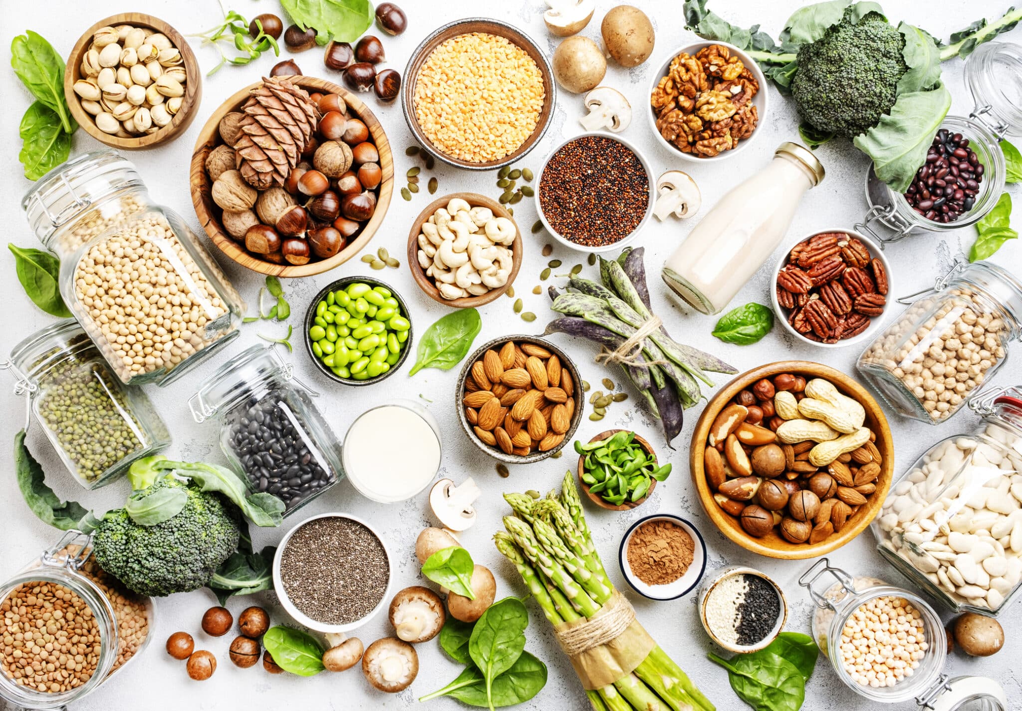 Különböző vegán, növényi alapú fehérjeforrások egy asztalon, felülről fotozóva: magvak, hüvelyesek, tofu, borsófehérje és még sok más.