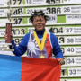 Budjargal Byambaa vegán ultramaraton futó az eredménytábla előtt, egyik kezével a kupáját fogja, másikkal a mongol zászlót
