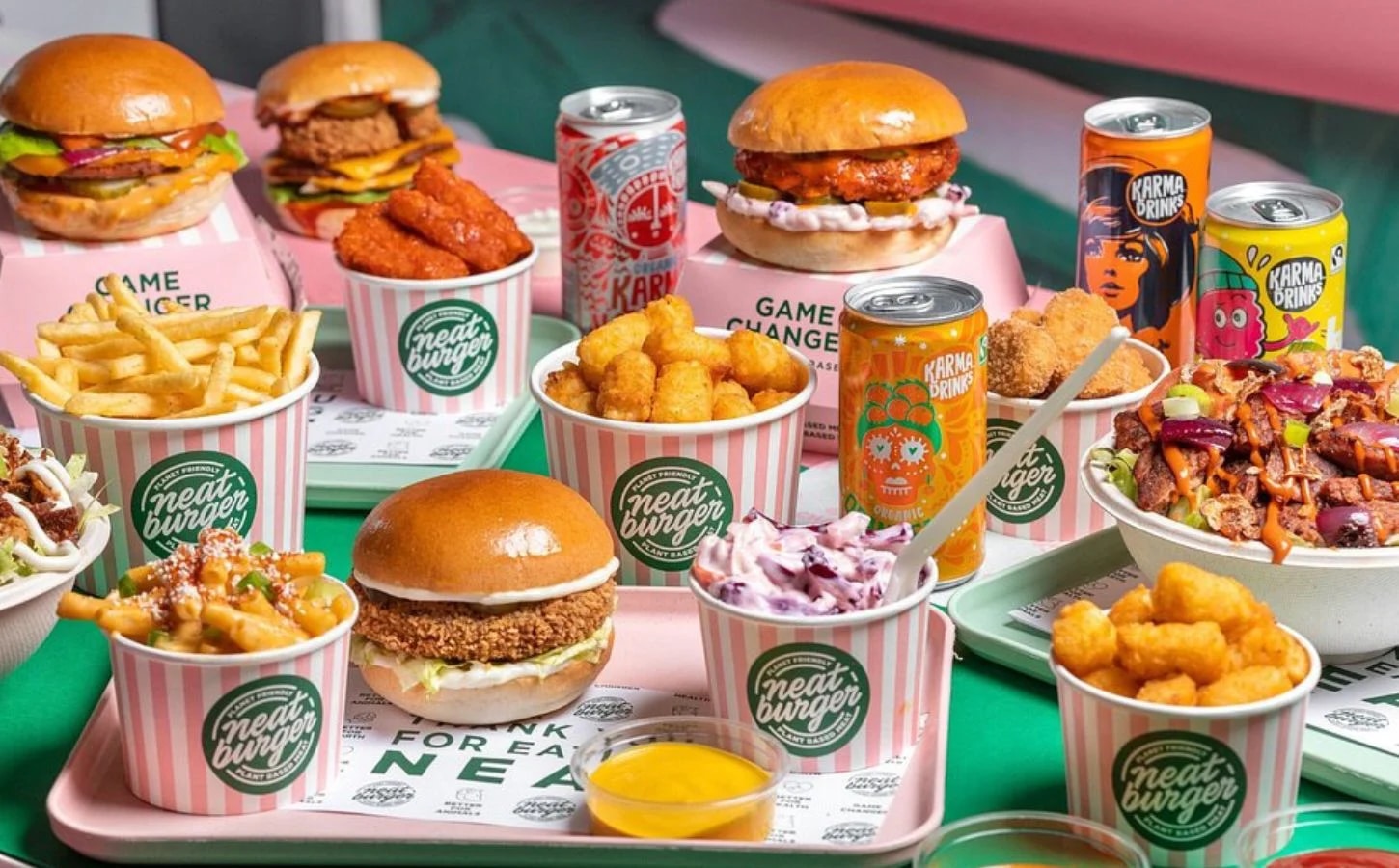 A Neat Burger vegán étteremlánc kínálata esztétikusan elrendezve egy asztalon, közte burgerek, fagylalt, sült krumpli, nuggets és dobozos szénsavas üdítők