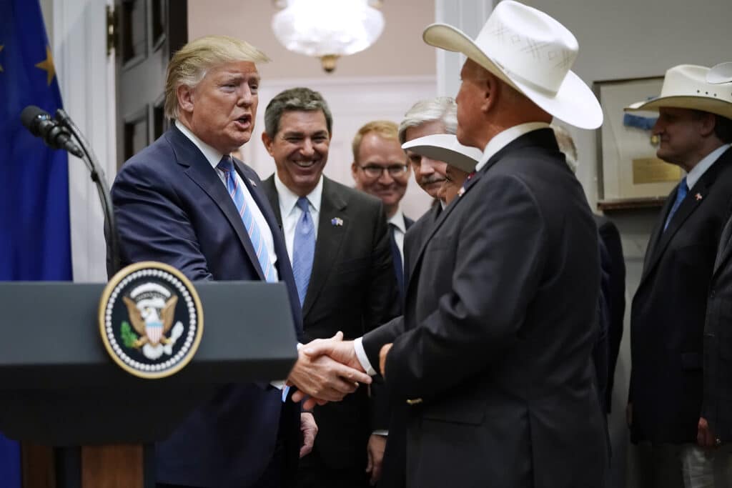Donald Trump kezet fog a National Cattlemen’s Beef Association érdekcsoport egyik vezetőjével, a háttérben az Európai Unió politikusai