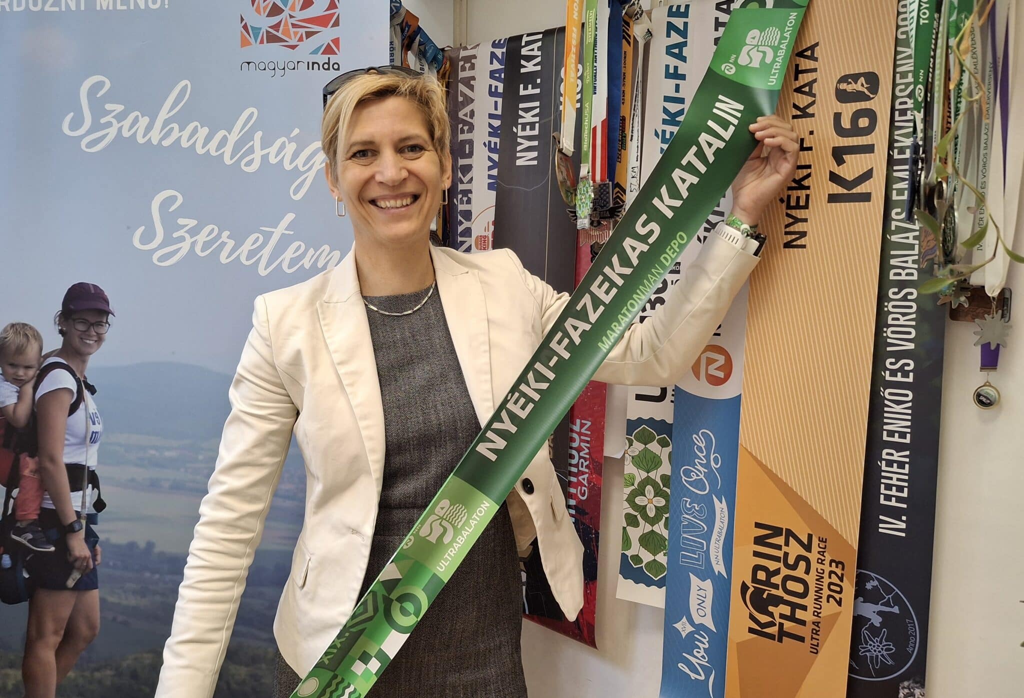 Nyéki-Fazekas Kata a 2025-ös UltraBalaton céljában kapott szalaggal, rajta a nevével.