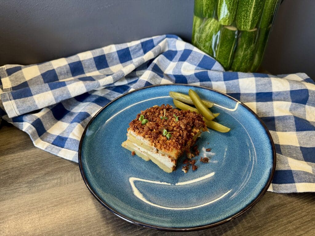 Kockára vágott rakott krumpli, mellette kovászos uborka.