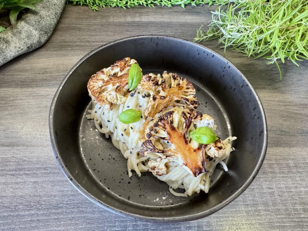 Tészta pirított karfiolszeletekkel, fekete tányéron