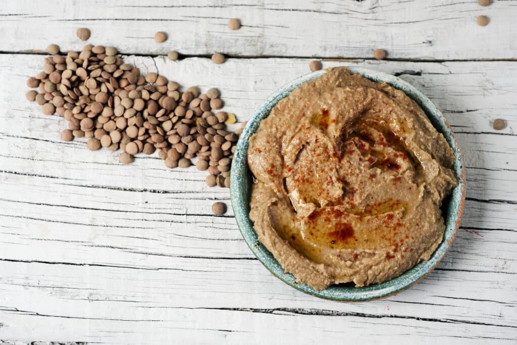 Lencsekrém kis tálban, mellette szétszórva egy sávban barna lencse