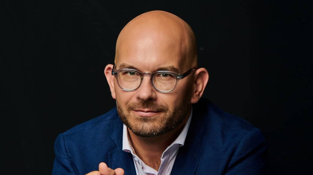 Bart István klímaszakértő ingben, öltönyben, fekete háttérrel