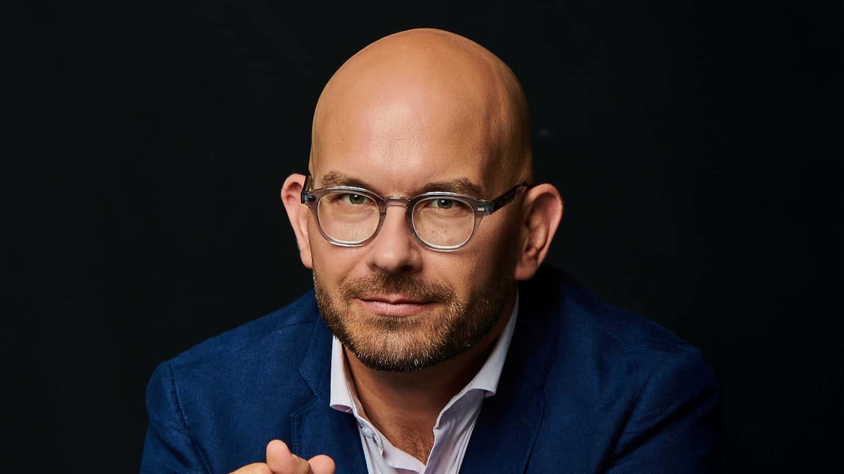 Bart István klímaszakértő ingben, öltönyben, fekete háttérrel