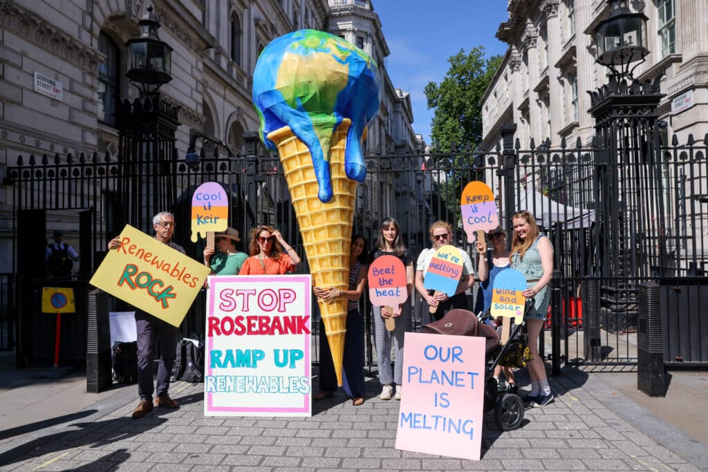 Klímatüntetők állnak transzparensekkel és egy nagy fagyival, amelyben egy olvadó Föld bolygó a gombóc