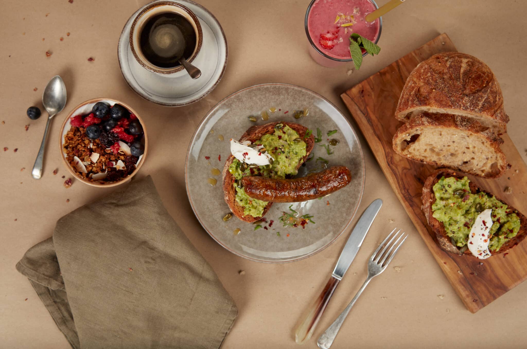 Sejttenyésztett húsból készült kolbász, zöld szendvicskrémmel megkent kenyér tetején, mellette kenyér, kávé