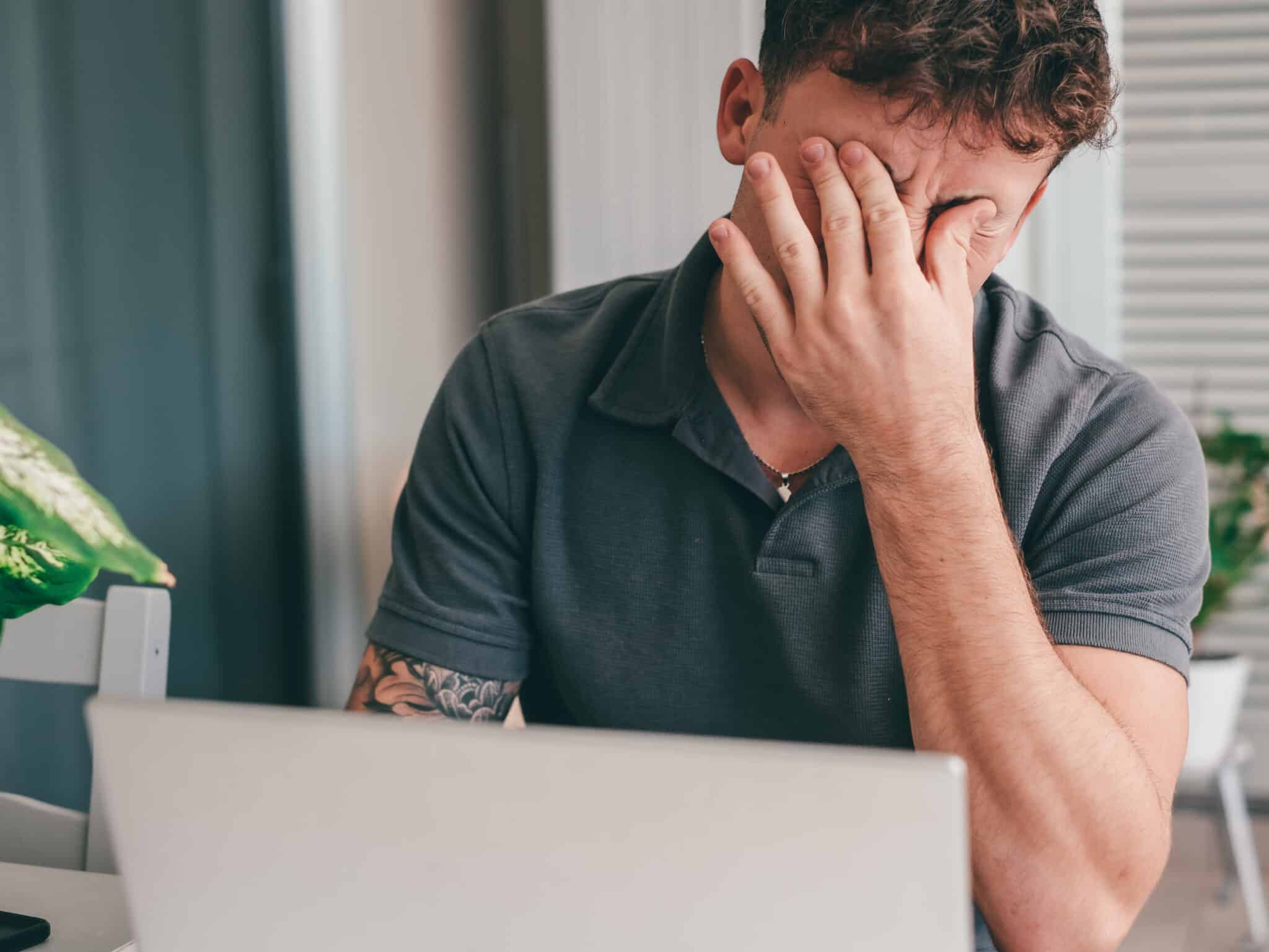 Szürke pólót viselő férfi ül a laptop előtt